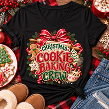 Load image into Gallery viewer, A black V-neck t-shirt with a festive 'Christmas Cookie Baking Crew' graphic, styled in a holiday flat-lay with jeans, slippers, cookies, and red plaid fabric.