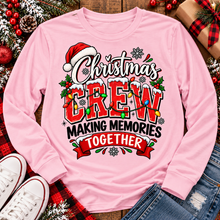 Load image into Gallery viewer, Christmas Crew Making Memories Together graphic on a pink crewneck T-shirt, featuring red lettering, colorful Christmas lights, a Santa hat, holly, and snowflakes.