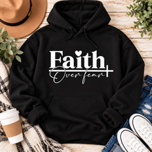 Load image into Gallery viewer, Faith Over Fear Christian inspirational graphic apparel featuring bold white Faith lettering, elegant Over Fear script, a small heart, and a cross design. Available in red and black in short sleeve crewneck, long sleeve crewneck, crewneck sweatshirt, and hoodie styles. Faith-based graphic clothing for women, everyday wear, church outfits, and inspirational gifts.