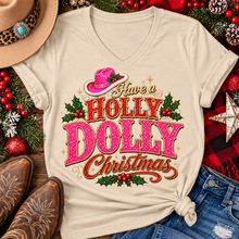 Load image into Gallery viewer, Have a Holly Dolly Christmas western graphic shirt featuring pink and red glitter-inspired lettering, a festive pink cowgirl hat, gold accents, and Christmas holly berries. Available in beige and pink in short sleeve crewneck, V-neck, long sleeve crewneck, and hoodie styles.