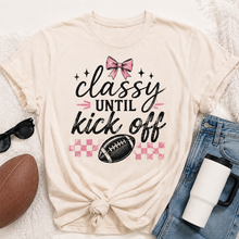 Load image into Gallery viewer, Cream crewneck Classy Until Kickoff football graphic tee featuring a pink bow, black football, pink checkerboard pattern and black and pink lettering.
