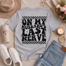 Load image into Gallery viewer, Gray crewneck graphic tee featuring oversized black āOn My Husbandās Last Nerveā lettering with retro checkerboard details on the back.