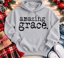 Load image into Gallery viewer, A light gray pullover hoodie with the words 'amazing grace.' printed in a black typewriter-style font across the chest.

