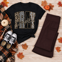 Load image into Gallery viewer, Black Pray Just Pray graphic T-shirt with leopard, cow print, checkerboard, and star lettering styled with brown leggings and fall accessories.
