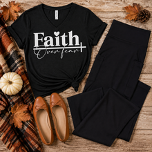Load image into Gallery viewer, Black Faith Over Fear V-neck graphic T-shirt styled in a fall flat lay with black cropped flare pocket pants, cognac ballet flats, a plaid scarf, autumn leaves, and a white pumpkin.
