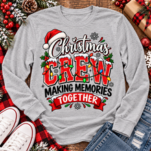 Load image into Gallery viewer, Christmas Crew Making Memories Together graphic on a pink crewneck T-shirt, featuring red lettering, colorful Christmas lights, a Santa hat, holly, and snowflakes.
