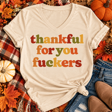 Load image into Gallery viewer, Funny Thankful for You Fuckers Thanksgiving graphic tee featuring bold retro lettering in burnt orange, mustard yellow, olive green, and rust red. Women's fall-inspired short sleeve crewneck shirt available in beige and brown, perfect for Thanksgiving and Friendsgiving.
