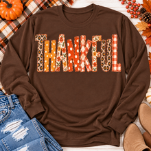 Load image into Gallery viewer, Brown long sleeve crewneck shirt featuring colorful Thankful patchwork lettering in retro autumn floral, plaid and polka dot patterns.
