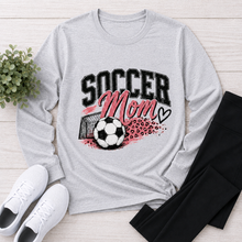 Load image into Gallery viewer, Gray crewneck long sleeve Soccer Mom graphic shirt with pink and black soccer design, styled with black leggings and white sneakers.
